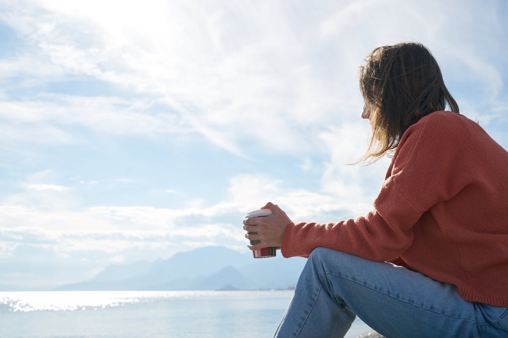 Proche aidante seule et pensive assise au bord d'un lac