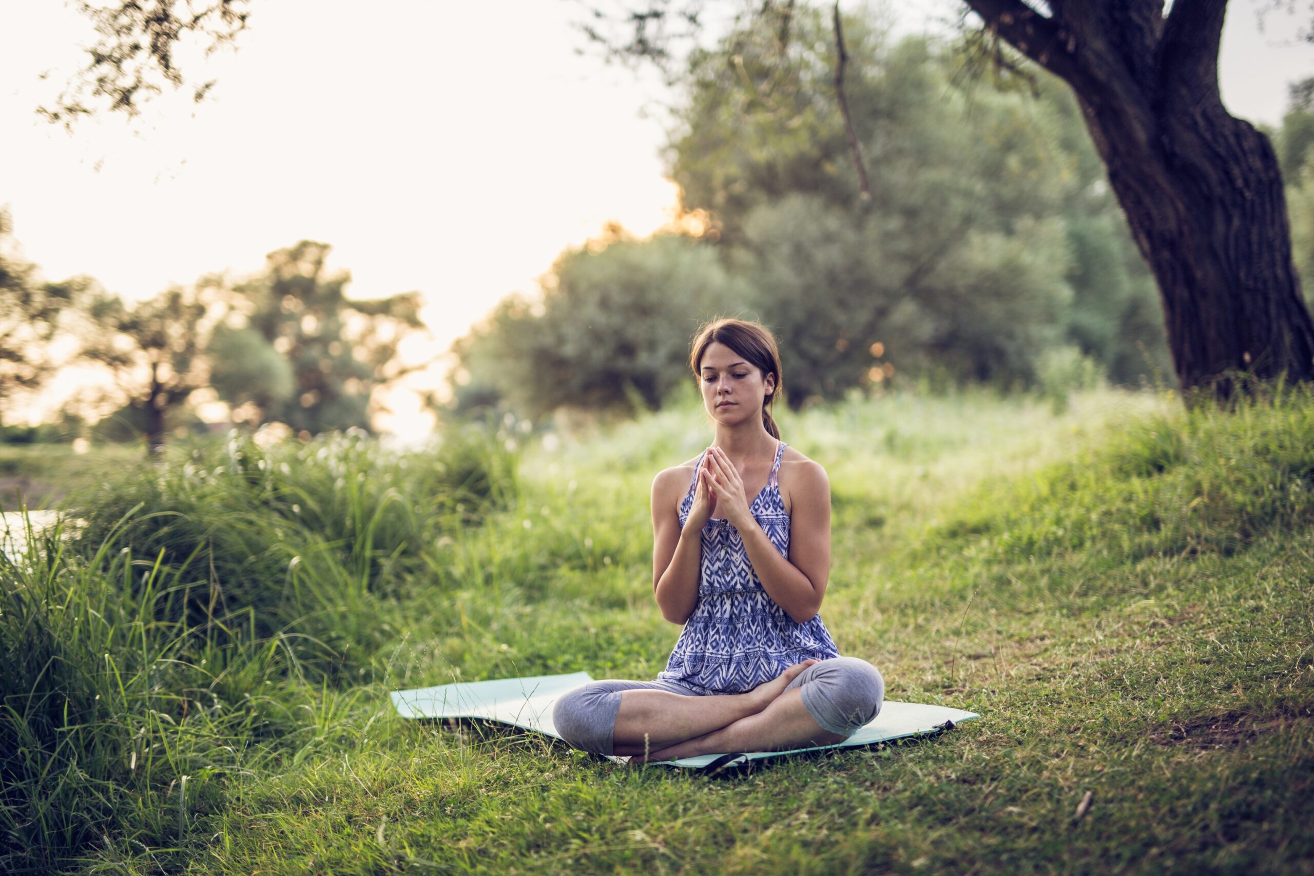 Femme qui médite assise dans un champ pour mieux gérer ses émotions et pratiquer la régulation émotionnelle